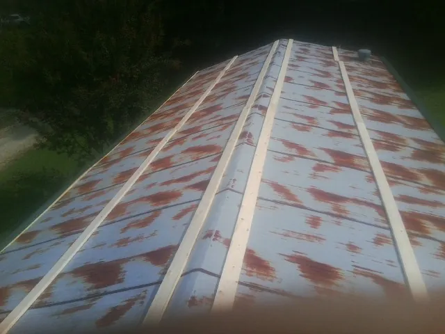 Rusted metal roof panels with new wood purlins before replacement — Storm Damage Roof Repair in Manor by Roofing Brothers