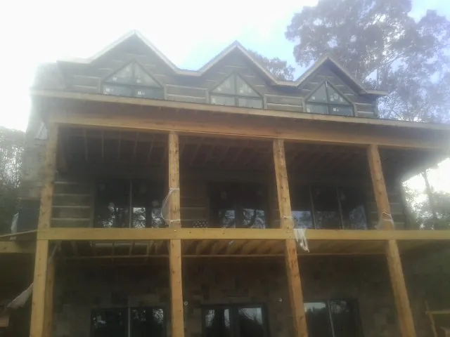 Dormers and porch framing on a large log home under construction — Roof Coating work by our crew in Manor