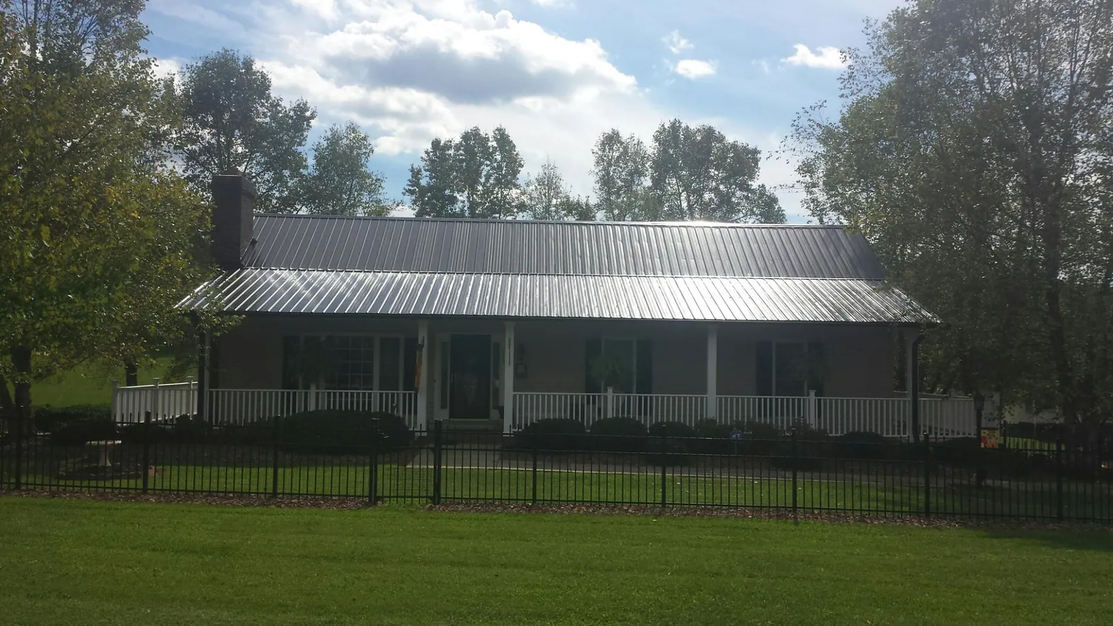 Gray metal roof on a brick ranch with a full width front porch — Gutter Guard Installation work by our crew in Manor