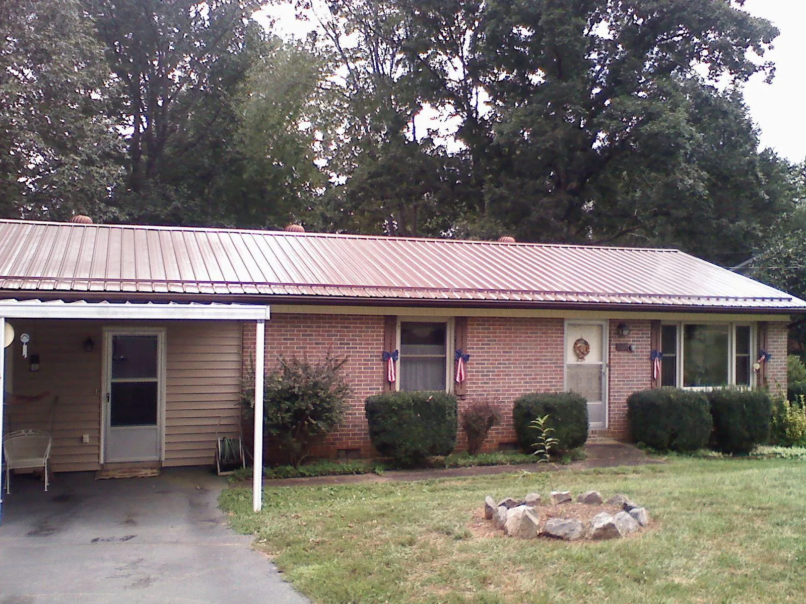 Bronze metal roof and carport on a brick ranch home — Roof Repair work by our crew in Manor