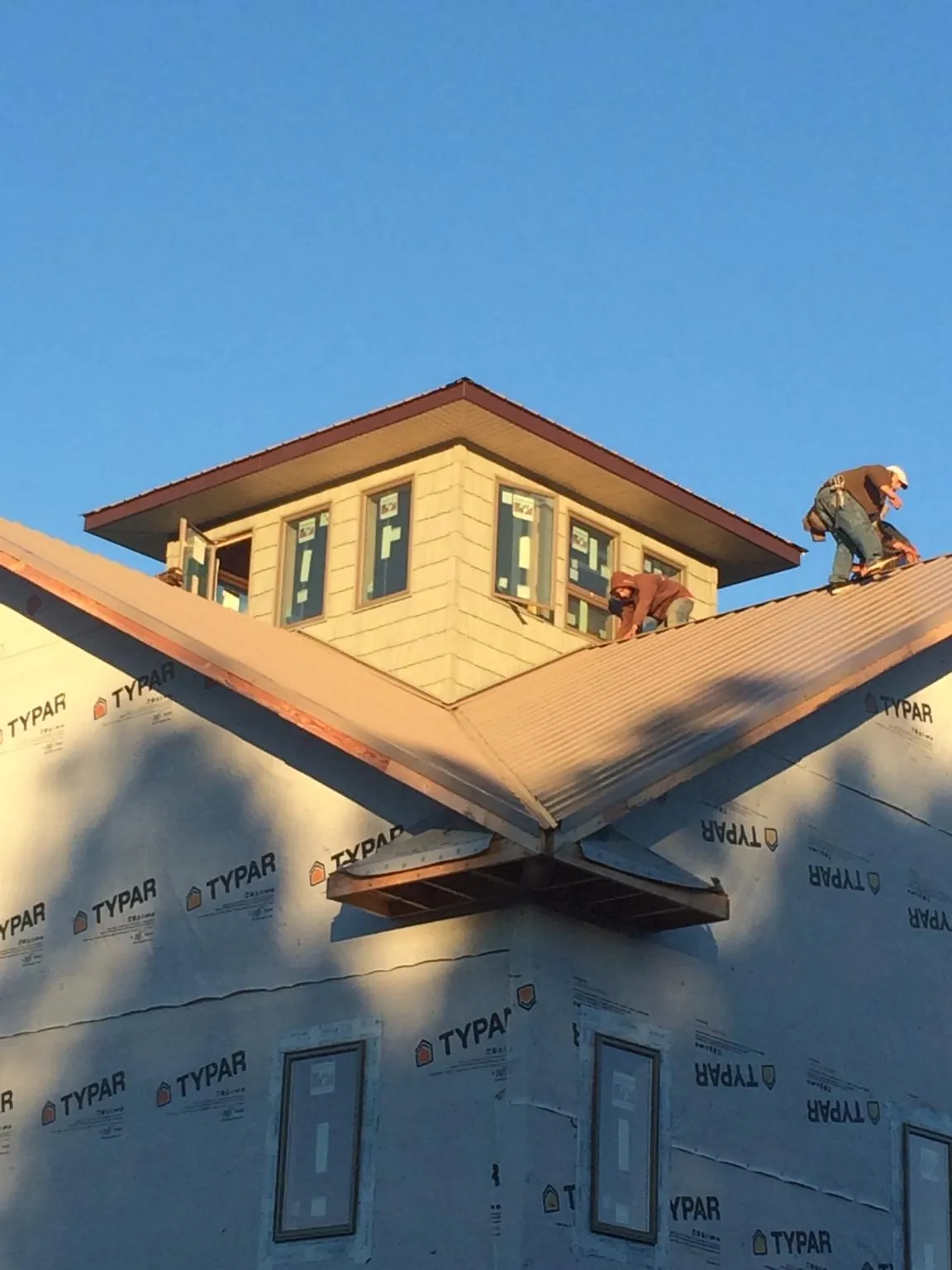 Roofers working around a rooftop cupola on a new metal roof at sunset — Roof Waterproofing in Manor by Roofing Brothers